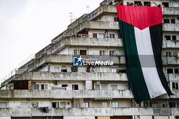 2023-10-18 - A large flag of about 30 metres with the colours of Palestine was displayed for a few minutes on the Vele in Scampia, at the initiative of activists of the Network for Palestine. About forty activists were present. The flag was displayed for a few minutes and then removed, attracting the attention of passers-by. - NAPLES, PRO-PALESTINE DEMONSTRATORS IN SCAMPIA - NEWS - CHRONICLE