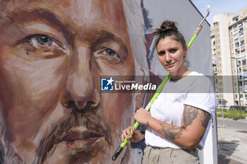 2023-10-18 - Trisha Palma napolitan street artist poses next to a portrait of Julian Assange, imprisoned in England awaiting extradition to the US because he is accused of leaking US national security information, The municipality of Naples will award Assange honorary citizenship - MURAL DEDICATED TO JULIAN ASSANGE IN NAPLES - NEWS - CHRONICLE