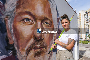 2023-10-18 - Trisha Palma napolitan street artist poses next to a portrait of Julian Assange, imprisoned in England awaiting extradition to the US because he is accused of leaking US national security information, The municipality of Naples will award Assange honorary citizenship - MURAL DEDICATED TO JULIAN ASSANGE IN NAPLES - NEWS - CHRONICLE