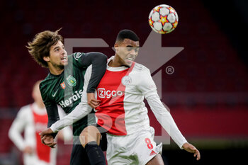 2021-12-07 - Daniel Braganca of Sporting CP battles for the ball with Ryan Gravenberch of Ajax during the UEFA Champions League, Group C football match between Ajax and Sporting Clube de Portugal on December 7, 2021 at Johan Cruijff ArenA in Amsterdam, Netherlands - AJAX VS SPORTING CLUBE DE PORTUGAL - UEFA CHAMPIONS LEAGUE - SOCCER