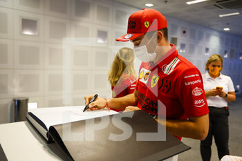 2021-12-09 - LECLERC Charles (mco), Scuderia Ferrari SF21, portrait signing helmet and book for TODT Jean (fra), FIA President during the Formula 1 Etihad Airways Abu Dhabi Grand Prix 2021, 22th round of the 2021 FIA Formula One World Championship from December 10 to 12, 2021 on the Yas Marina Circuit, in Yas Island, Abu Dhabi - FORMULA 1 ETIHAD AIRWAYS ABU DHABI GRAND PRIX 2021, 22TH ROUND OF THE 2021 FIA FORMULA ONE WORLD CHAMPIONSHIP - FORMULA 1 - MOTORS
