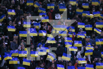 2022-03-01 - Fans hold up cards bearing the word 'peace' on a background of yellow and blue to represent the Ukraine national flag during the Coppa Italia 2021/22 football match between AC Milan and FC Internazionale at Giuseppe Meazza Stadium, Milan, Italy on March 01, 2022 - AC MILAN VS FC INTERNAZIONALE - ITALIAN CUP - SOCCER