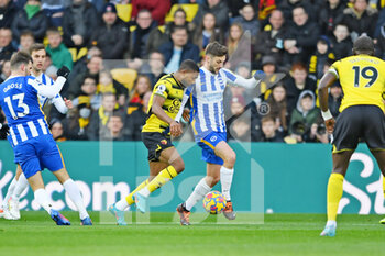 2022-02-12 - Watford forward Emmanuel Dennis (25) and Brighton and Hove Albion midfielder Adam Lallana (14) during the English championship Premier League football match between Watford and Brighton and Hove Albion on February 12, 2022 at Vicarage Road in Watford, England - WATFORD VS BRIGHTON AND HOVE ALBION - ENGLISH PREMIER LEAGUE - SOCCER