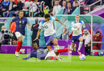 2022-12-10 - Ousmane Dembele (11) of France slides in and tackles Jude Bellingham (22) of England during the FIFA World Cup 2022, Quarter-final football match between England and France on December 10, 2022 at Al Bayt Stadium in Al Khor, Qatar - FOOTBALL - WORLD CUP 2022 - 1/4 - ENGLAND V FRANCE - FIFA WORLD CUP - SOCCER