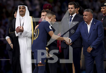 2022-12-18 - Kylian Mbappe of France is consoled by President of France Emmanuel Macron while Emir of Qatar Sheikh Tamim bin Hamad Al Thani (left), AFA President Claudio Tapia look on during the trophy ceremony following the FIFA World Cup 2022, Final football match between Argentina and France on December 18, 2022 at Lusail Stadium in Al Daayen, Qatar - FOOTBALL - WORLD CUP 2022 - FINAL - ARGENTINA V FRANCE - FIFA WORLD CUP - SOCCER