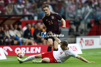 2023-06-16 - Florian Wirtz of Germany Tomasz Kedziora of Poland during the International Friendly Football match between Poland and Germany on June 16, 2023 at PGE Narodowy in Warsaw, Poland - FOOTBALL - FRIENDLY GAME - POLAND V GERMANY - FRIENDLY MATCH - SOCCER
