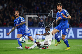 2023-03-23 - Bukayo Saka of England (C) kicks the ball under pressure from Leonardo Spinazzola (L) and Francesco Acerbi (R) of Italy during the UEFA Euro 2024, European Qualifiers, Group C football match between Italy and England on March 23, 2023 at Stadio Diego Armando Maradona in Naples, Italy - FOOTBALL - EURO 2024 - QUALIFYING - ITALY V ENGLAND - UEFA EUROPEAN - SOCCER