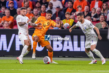 2023-10-13 - Tijjani Reijnders of the Netherlands is challenged by Jonathan Clauss of France and Lucas Hernandez of France during the UEFA Euro 2024, Qualifiers Group B football match between Netherlands and France on October 13, 2023 at Johan Cruijff ArenA in Amsterdam, Netherlands - FOOTBALL - EURO 2024 - QUALIFYING - NETHERLANDS V FRANCE - UEFA EUROPEAN - SOCCER