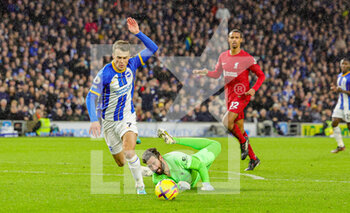 2023-01-14 - Alisson Becker (1) of Liverpool brings down Solly March (7) of Brighton & Hove Albion during the English championship Premier League football match between Brighton and Hove Albion and Liverpool on January 14, 2023 at the American Express Community Stadium in Brighton and Hove, England - FOOTBALL - ENGLISH CHAMP - BRIGHTON V LIVERPOOL - ENGLISH PREMIER LEAGUE - SOCCER