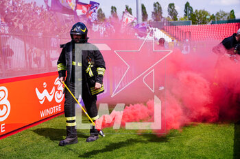 2023-04-23 - A firefighter picks up a smoke bomb thrown by fans at the edge of the pitch - AC MONZA VS ACF FIORENTINA - ITALIAN SERIE A - SOCCER