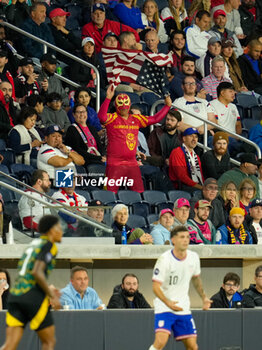 2024-11-18 - A fan of the United States waves a flag in the crowd behind Jamaica forward Leon Bailey (7) and United States forward Christian Pulisic (10) - CONCACAF NATIONS LEAGUE - USA VS JAMAICA - OTHER - SOCCER