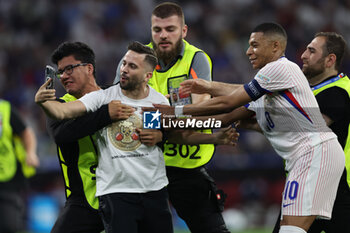 2024-07-09 - Munich , Germany 09.07.2024: fan invades the pitch to take a photograph with Kylian Mbappe of France during the UEFA EURO 2024 semi-finals, football match between Spain vs France at Munich Football Allianz Arena - UEFA EURO 2024 - SEMIFINALS - SPAIN VS FRANCE  - UEFA EUROPEAN - SOCCER