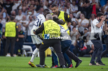 2024-05-08 - MADRID, SPAIN - MAY 8: A fan is escorted off after invading the pitch at the end of the UEFA Champions League semi-final second leg match between Real Madrid and FC Bayern Munchen at Estadio Santiago Bernabeu on May 8, 2024 in Madrid, Spain. - REAL MADRID VS BAYERN MUNICH - UEFA CHAMPIONS LEAGUE - SOCCER