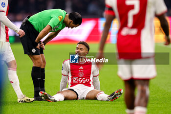 2024-02-03 - Devyne Rensch of Ajax sitting on the pitch injured during the Netherlands championship Eredivisie football match between AFC Ajax and PSV on February 3, 2024 at Johan Cruijff ArenA in Amsterdam, Netherlands - FOOTBALL - NETHERLANDS CHAMP - AJAX V PSV - NETHERLANDS EREDIVISIE - SOCCER