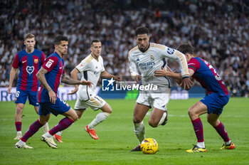 2024-04-21 - MADRID, SPAIN - APRIL 21: Jude Bellingham of Real Madrid (C) seen in action against Pau Cubarsi of FC Barcelona (R) and Joao Cancelo of FC Barcelona (L) during the La Liga EA Sports 2023/24 football match between Real Madrid vs FC Barcelona at Estadio Santiago Bernabeu on April 21, 2024 in Madrid, Spain. - REAL MADRID VS FC BARCELONA - SPANISH LA LIGA - SOCCER