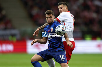 2024-10-15 - Martin Baturina of Croatia and Jakub Moder of Poland during the UEFA Nations League, League A, Group A1 football match between Poland and Croatia on 15 October 2024 at PGE Narodowy stadium in Warsaw, Poland - FOOTBALL - UEFA NATIONS LEAGUE - POLAND V CROATIA - UEFA NATIONS LEAGUE - SOCCER