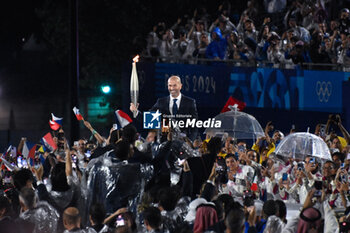 2024-07-26 - Zinadine Zidane with the Olympic torch, Opening Ceremony during the Olympic Games Paris 2024 on 26 July 2024 in Paris, France - OLYMPIC GAMES PARIS 2024 - OPENING CEREMONY - 26/07 - OLYMPIC GAMES PARIS 2024 - OLYMPIC GAMES