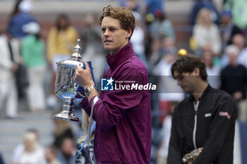 2024-09-08 - Winner Jannik Sinner of Italy celebrates while Taylor Fritz of USA looks on during the trophy ceremony of the men's final on day 14 of the 2024 US Open, Grand Slam tennis tournament on September 8, 2024 at USTA Billie Jean King National Tennis Center in Flushing Meadows, Queens, New York, United States - TENNIS - US OPEN 2024 - 08/09 - INTERNATIONALS - TENNIS