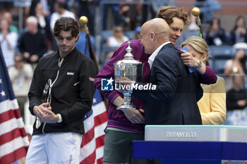 2024-09-08 - Winner Jannik Sinner of Italy receives the trophy from Andre Agassi while finalist Taylor Fritz of USA (L) looks on during the trophy ceremony of the men's final on day 14 of the 2024 US Open, Grand Slam tennis tournament on September 8, 2024 at USTA Billie Jean King National Tennis Center in Flushing Meadows, Queens, New York, United States - TENNIS - US OPEN 2024 - 08/09 - INTERNATIONALS - TENNIS