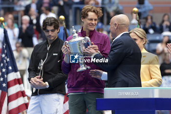 2024-09-08 - Winner Jannik Sinner of Italy receives the trophy from Andre Agassi while finalist Taylor Fritz of USA (L) looks on during the trophy ceremony of the men's final on day 14 of the 2024 US Open, Grand Slam tennis tournament on September 8, 2024 at USTA Billie Jean King National Tennis Center in Flushing Meadows, Queens, New York, United States - TENNIS - US OPEN 2024 - 08/09 - INTERNATIONALS - TENNIS