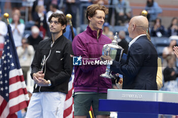 2024-09-08 - Winner Jannik Sinner of Italy receives the trophy from Andre Agassi while finalist Taylor Fritz of USA (L) looks on during the trophy ceremony of the men's final on day 14 of the 2024 US Open, Grand Slam tennis tournament on September 8, 2024 at USTA Billie Jean King National Tennis Center in Flushing Meadows, Queens, New York, United States - TENNIS - US OPEN 2024 - 08/09 - INTERNATIONALS - TENNIS