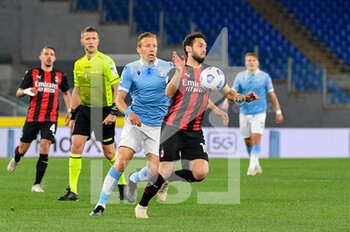 2021-04-26 - Hakan Calhanoglu of AC Milan and Lucas Leiva of SS Lazio seen in action during the Italian Football Championship League A 2020/2021 match between SS Lazio vs AC Milan at the Olimpic Stadium in Rome. - SS LAZIO VS AC MILAN - ITALIAN SERIE A - SOCCER
