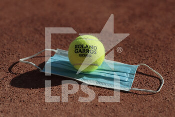 2020-09-21 - Illustration of official tennis ball Roland Garros 2020 by Wilson on the clay of Philippe Chatrier court over protector mask under the CoVid health crisis 19 during the Roland Garros 2020, Grand Slam tennis tournament, Qualifying, on September 21, 2020 at Roland Garros stadium in Paris, France - Photo Stephane Allaman / DPPI - ROLAND GARROS 2020, GRAND SLAM - QUALIFYING - INTERNATIONALS - TENNIS